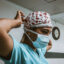 Healthcare worker in scrubs putting on a surgical mask